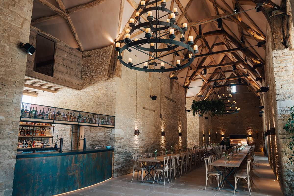 Ivy Lodge restored barn dining hall with copper bar, oak beams, chandeliers, and long banquet tables